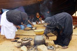 Image du Maroc Professionnelle de  Sous une tente bédouine plusieurs femmes du Sahara  préparent le couscous durant le grand Moussem de Tan Tan, classé en 2005 patrimoine immatériel humain mondial de l'Unesco. Le Moussem est une sorte de foire annuelle, à la fois économique, culturelle et sociale. Chaque année la majorité des tribus et des grandes familles nomades du désert se retrouvent sur un site désertique "Place de la Tolérance et de la Paix " à la périphérie de Tan Tan où  danse, chants, course de chameaux et fantasia font partie des festivités. , Samedi 18 septembre 2004, ((Photo / Abdeljalil Bounhar) 